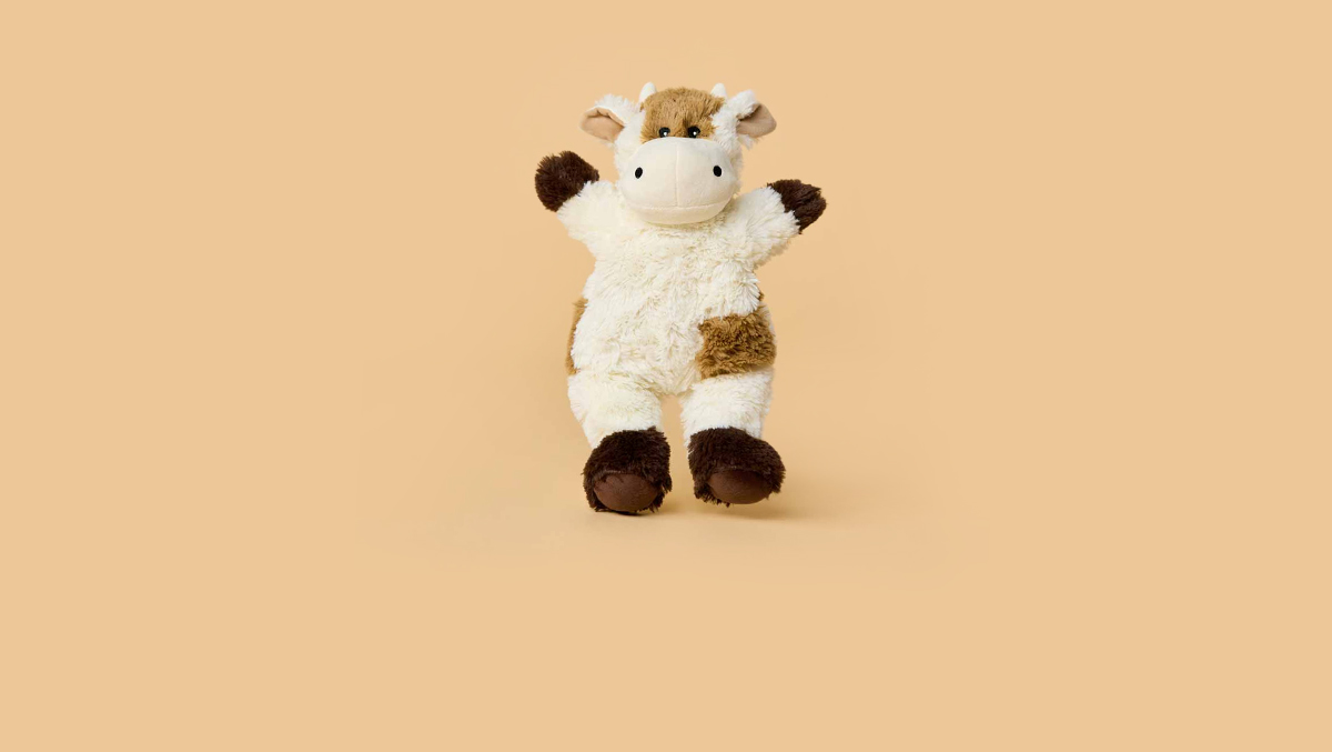 Child sitting on the floor surrounded by Microwavable, Scented, Weighted Warmies Stuffed Animals.